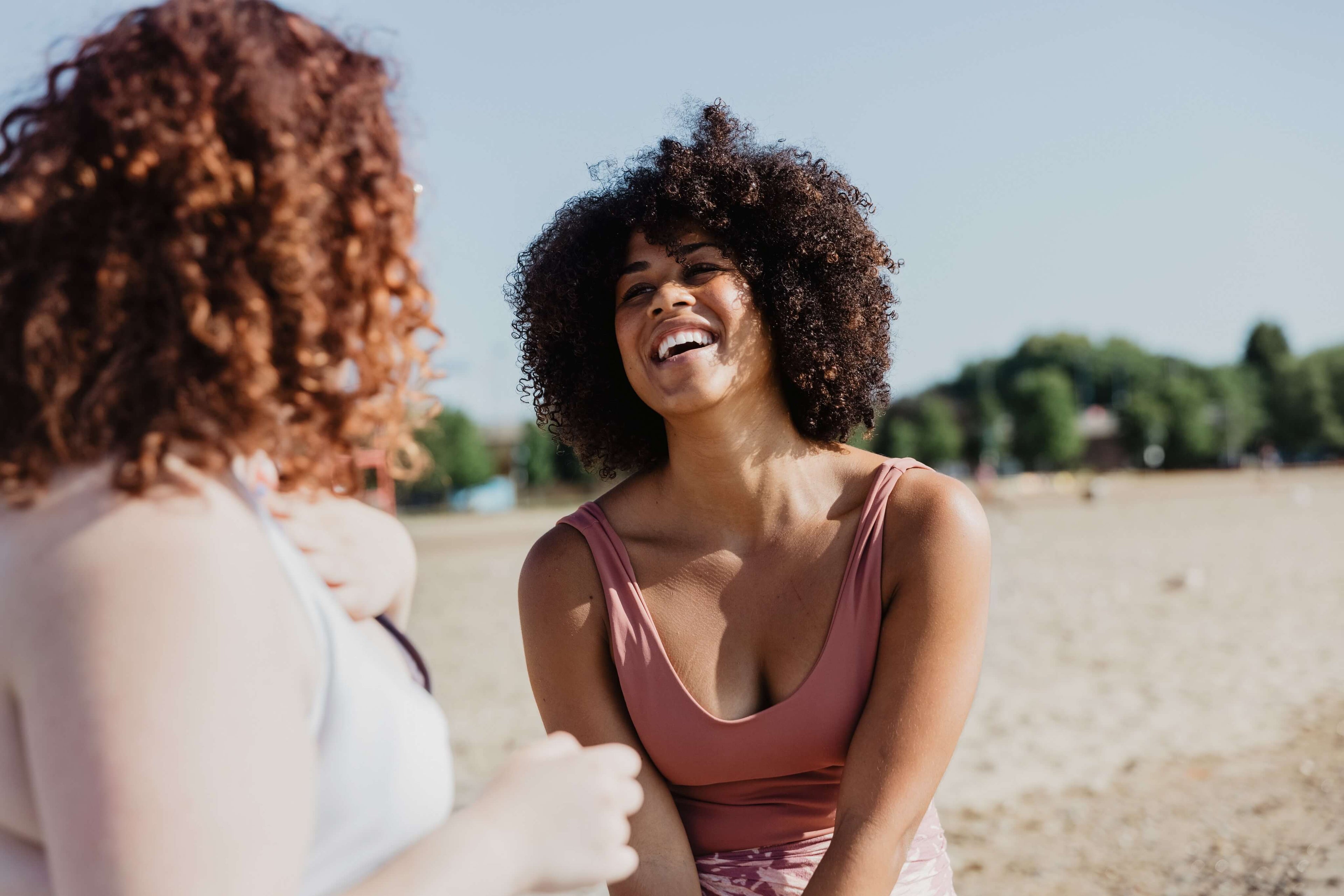 A young woman in a bikini laughs joyfully with friends, capturing a carefree summer moment filled with fun, energy, and sunshine vibes.